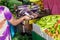 Female buyer paying with cash after buying vegetables at the Male market in Maldives