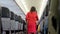 Female cabin crew with service cart serving passengers in aircraft corridor. flight attendant in red uniform working at airplane a