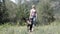 Female with cap on walking in the nature on a spring day with her chocolate Labrador retriever while .