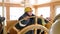 Female captain turning steering wheel in navigation bridge at floating ship. Woman sailor steering helm of sailing boat