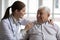 Female caregiver doctor supporting smiling older man, touching shoulders