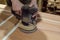 Female carpenter polishes the wooden door surface with electric grinding machine