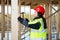 Female Carpenter In Reflective Jacket Hammering Nail In Wood