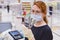 A female cashier in a medical mask counts money against the background of the cash register. Dollars in the hands of the seller in