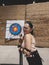 A female casual hobbyist posing behind her Archery Target Face Sheet at an indoor archery range