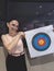 A female casual hobbyist posing with her Archery Target Face Sheet at an indoor archery range