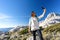 Female Caucasian hiker reaching the mountain peak take a self portrait with smartphone. Active woman with sunglasses and backpack