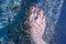 Female caucasian leg and feet in the water in thermal Lake Vouliagmeni in Athens, Greece with rufa garra fish making pedicure