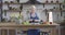 Female caucasian retiree peeling cucumber with kitchen knife and looking into recipe book. Senior woman in apron cooking