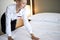 Female chambermaid making bed in hotel room