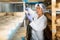 Female cheesemaker checks the quality of the cheese. Numbers on white pieces of paper are date when cheese was put into