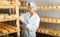 Female cheesemaker checks the quality of the cheese. Numbers on white pieces of paper are date when cheese was put into