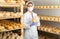 Female cheesemaker in protective mask checks the quality of the cheese.