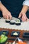 Female chef cutting japanese sushi roll