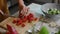 Female chef hands cut the tomato into cubes on wooden cutting board for salad. Rbbro slice and chop