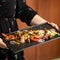 Female chef holding tray with steaming vegetables. Vegetarian Dish in Asian restaurant. Spicy oriental bright, colors or