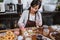 Female chef wears an apron as she sprinkles donuts with chocolate in the kitchen