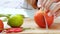 Female chief cutting tomato into pieces with knife on wooden chopping board.