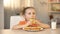 Female child eating tasty donut, milk glass on table, sweet snack, nutrition