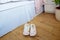 Female or child pink comfort slippers on the wooden floor near the bed. Funny home kitty slippers. Morning habits