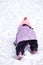 Female child while playing and crawling snow in a ski resort