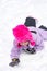 Female child while playing and crawling snow in a ski resort