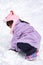 Female child while playing and crawling snow in a ski resort