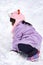 Female child while playing and crawling snow in a ski resort