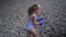 Female child in swimsuit carry bucket with water through beach