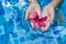 Female Childs hands holding a pink flower while floating on a pool water