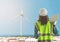 Female Civil engineer with computer is standing in front on wind turbine for Sustainable energy industry development