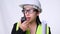 Female civil engineer in a helmet holding construction plans and using walkie-talkie and talk to other staff on a white background