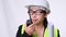 Female civil engineer in a helmet holding construction plans and using walkie-talkie and talk to other staff on a white background