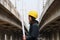 Female civil engineer with yellow helmet, standing side to side with project drafts while in hand on parallel expressway