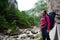 Female climber admiring amazing view of green grassy rocky mountains and water stream in mountainous area in Romania