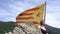 A female climber has reached the summit and is resting against the backdrop of the Catalan flag