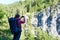 Female climber making picture of spectacular green rock with high trees on top