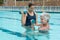 Female coach assisting senior woman in lifting dumbbells