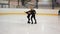 Female coach in figure skating training little girl at indoor rink