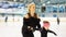 Female coach in figure skating training little girl at indoor rink