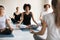 Female coach training diverse people, practicing yoga, doing Padmasana exercise