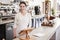 Female coffee shop owner standing behind counter smiling