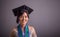 Female college student in graduation hat closeup portrait over grey