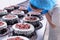 Female confectioner decorates sponge chocolate cakes with fresh cherry berry cream. Cake Making Confectionery, business