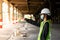 Female construction engineer Asians wearing safety hats and green vests stand to watch work and point fingers at a construction