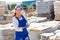 Female construction store clerk demonstrates natural stone tiles on open-air site