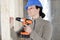 female construction worker having driller tool drilling wall
