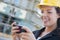 Female Contractor Wearing Hard Hat on Site Texting with Phone