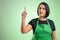 Female cook with green apron and black t-shirt with her finger up has come up with an idea