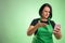 Female cook with green apron and black t-shirt holding smartphone, texting, looking nervously